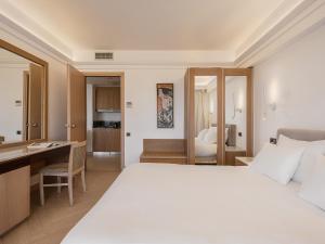 a hotel room with a large bed and a desk at Porto Platanias Beach Resort & Spa in Plataniás