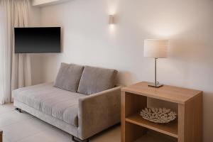 a living room with a couch and a table with a lamp at Porto Platanias Beach Resort & Spa in Plataniás