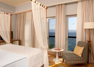 a bedroom with a bed and a chair and windows at Xanadu Island in Akyarlar