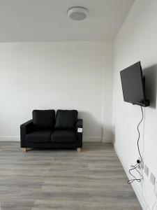 a living room with a black couch and a television at Train Station Apartments- 2 Beds-1 Beds in Scunthorpe