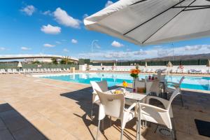 a patio with a table and chairs and a pool at RT-Green Park in Playa del Ingles +49 photos