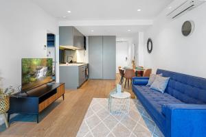 メルボルンにあるElegant High Rise 2 Bed Apt near Melb CBD RMITの青いソファとキッチンのあるリビングルーム