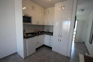 a kitchen with white cabinets and black counter tops at Casa Linda in Costa Teguise