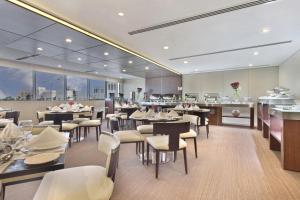 多哈White Square Curve Hotel & Suites的有桌椅和酒吧的餐厅