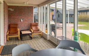 a screened porch with two chairs and a table at Cozy Home In Fårevejle in Fårevejle