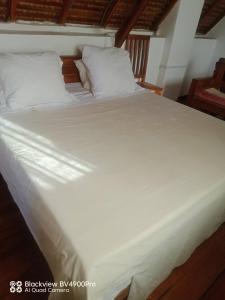 a large white bed with white sheets and pillows at My Little House in Mandriankeniheny +6 photos