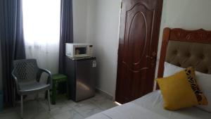 - une chambre avec un lit, un four micro-ondes et une chaise dans l'établissement Mazuri Homes,Ujamaa Building, à Gatunga