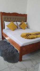 un lit en bois avec des oreillers jaunes et une couverture dessus dans l'établissement Mazuri Homes,Ujamaa Building, à Gatunga