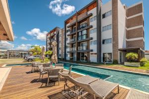 an apartment building with a swimming pool and chairs at Apartamentos em Condomínio com Piscina e Academia - AGA in Camaçari