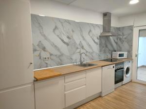 eine Küche mit weißen Schränken und einer Marmorwand in der Unterkunft Villamolinos, villa con piscina privada. in San Pedro del Pinatar