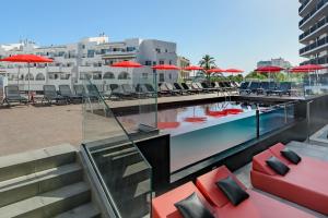 basen z leżakami i parasolami w budynku w obiekcie Hotel Vibra District - Adults Only w mieście San Antonio