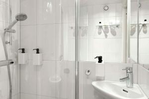 a white bathroom with a shower and a sink at Scandic Malmen in Stockholm