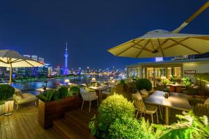 上海上海外滩悦榕庄 - 顶楼露台Tales餐厅酒吧纵览浦江美景的一间晚上带桌子和遮阳伞的餐厅