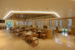 a restaurant with tables and chairs and windows at Lemon Tree Hotel, Chinchwad, Pune in Pune +4 photos