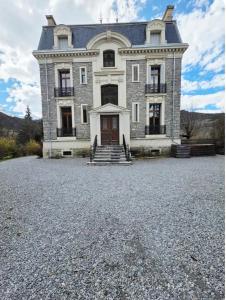 a large stone house with a large driveway at Appartement au rez de jardin d'une villa Mexicaine in Barcelonnette