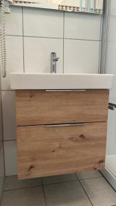 a bathroom with a white sink and a wooden drawer at Haus Jenny, Wohnung E3b, Sonne rundum in Boltenhagen