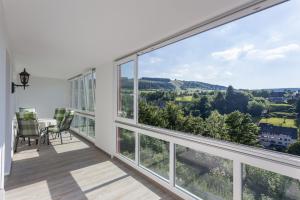 a balcony with large windows and a table and chairs at Belvita Ferienwohnung 1 mit Hallenbad & Sauna in Willingen +26 photos