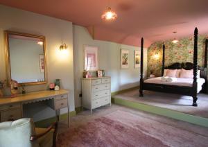 Schlafzimmer mit einem Bett, einem Schreibtisch und einem Spiegel in der Unterkunft The Maze Garden Cottage by Mint Stays in Biddlestone