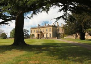 ein großes Haus mit einem Baum davor in der Unterkunft The Maze Garden Cottage by Mint Stays in Biddlestone