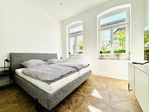Un dormitorio blanco con una cama y dos ventanas. en Villa Maria # 1, en Bad Oeynhausen