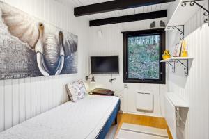 une petite chambre avec un lit et une télévision dans l'établissement Cozy Nature Getaway Just Minutes From Ebeltoft And Top Attractions, à Ebeltoft