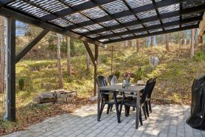 un patio avec une table et des chaises sous une pergola dans l'établissement Cozy Nature Getaway Just Minutes From Ebeltoft And Top Attractions, à Ebeltoft