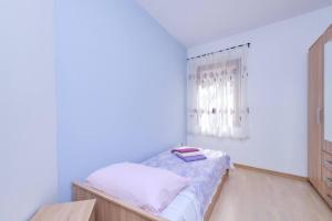 a small bedroom with a bed and a window at Apartment Dino 1 in Mali Lošinj