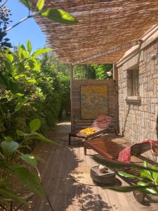 un patio avec une table et un banc sous un toit dans l'établissement MarVivo Villa - Rez de Jardin - Plage 3' à pied, à La Seyne-sur-Mer