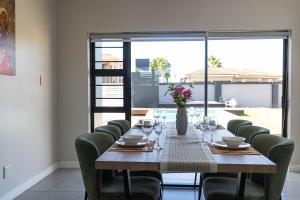 a wooden table with chairs and a vase of flowers at Bluewater Bay Escape in Gqeberha