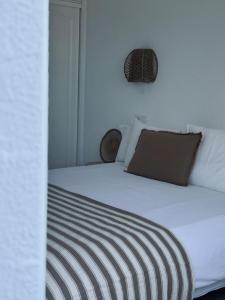 a bed with white sheets and a brown pillow at Sand House Doñana - Free beach club access to Kai Club in Patalavaca