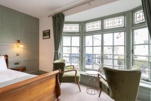 a bedroom with a bed and chairs and windows at The Bugle Coaching Inn in Yarmouth