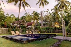 a villa with a swimming pool and palm trees at La Royale Nusa Penida in Nusa Penida