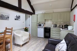a kitchen with green cabinets and a couch in a room at Church Farm Country Cottages in Freshford