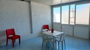 a dining room with red chairs and a white table at appartamento a due passi dal mare in San Vito lo Capo