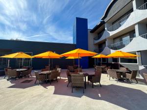 a patio with tables and chairs with yellow umbrellas at Comfort Suites Kingston Central in Kingston