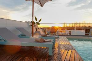 a deck with a bench and an umbrella next to a pool at Wood Beach in Monte Gordo