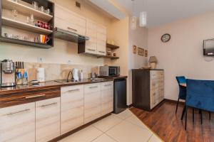 a kitchen with white cabinets and a blue chair at Lazurowy Dwór - Królewski Sen by Grand Apartments in Sztutowo +19 photos