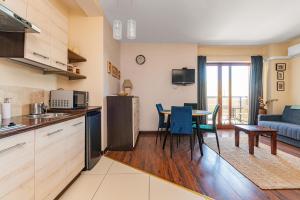 a kitchen and living room with a table and chairs at Lazurowy Dwór - Królewski Sen by Grand Apartments in Sztutowo