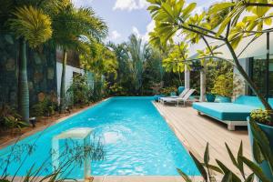 a swimming pool in a backyard with a blue couch and palm trees at Villa Ayana - Premium Mauritius Stay in Grand Baie +39 photos