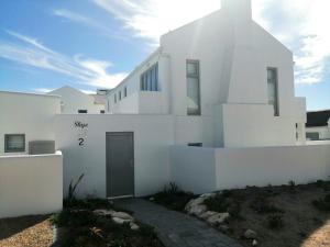 a white house with a door on the side of it at Skye in Paternoster