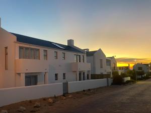 a house on a street with the sunset in the background at Skye in Paternoster