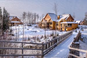a group of houses in the snow with a fence at Havre Ride-Out 113 Luxurious & Modern Direct Ski-in Ski-out in Mont-Tremblant