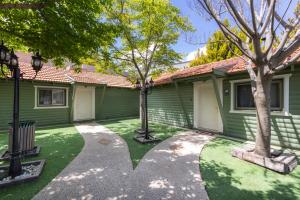 uma casa verde com árvores no quintal em בקתות עץ מעל העננים - אירוח דרוזי - בקתות כפריות עם נוף מהמם ובריכה מחוממת מקורה משותפת em Beit Jann