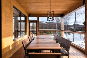 a dining room with a long wooden table and benches at Havre 117 Tremblant Luxurious & Modern Ski-in Ski-out in Mont-Tremblant