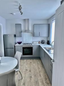 cocina con armarios blancos y mesa blanca en Beautifully Spacious 3 Bed Home, en Kenton