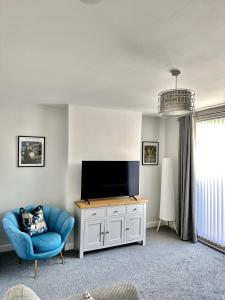 sala de estar con TV y silla azul en Beautifully Spacious 3 Bed Home, en Kenton