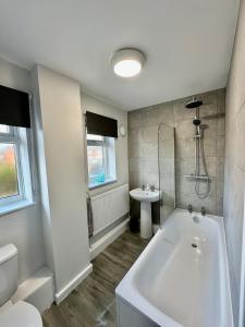 Un baño blanco con bañera y lavabo. en Beautifully Spacious 3 Bed Home, en Kenton