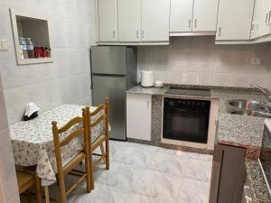 a kitchen with a table and a stainless steel refrigerator at Casa centro histórico de Viveiro in Viveiro