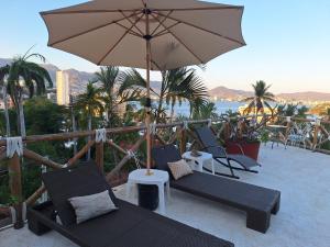 un gruppo di sedie e un ombrellone su un balcone di Casa Breizh ad Acapulco