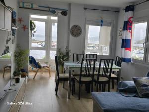 a dining room and living room with a table and chairs at Apartamento Malecón in Muxia